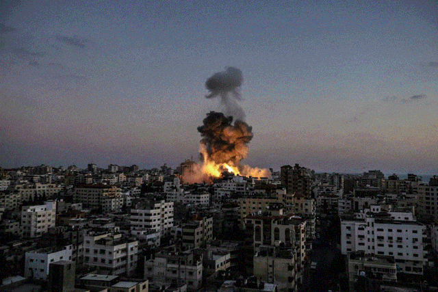 Explosion and smoke rising over a city skyline at dusk.