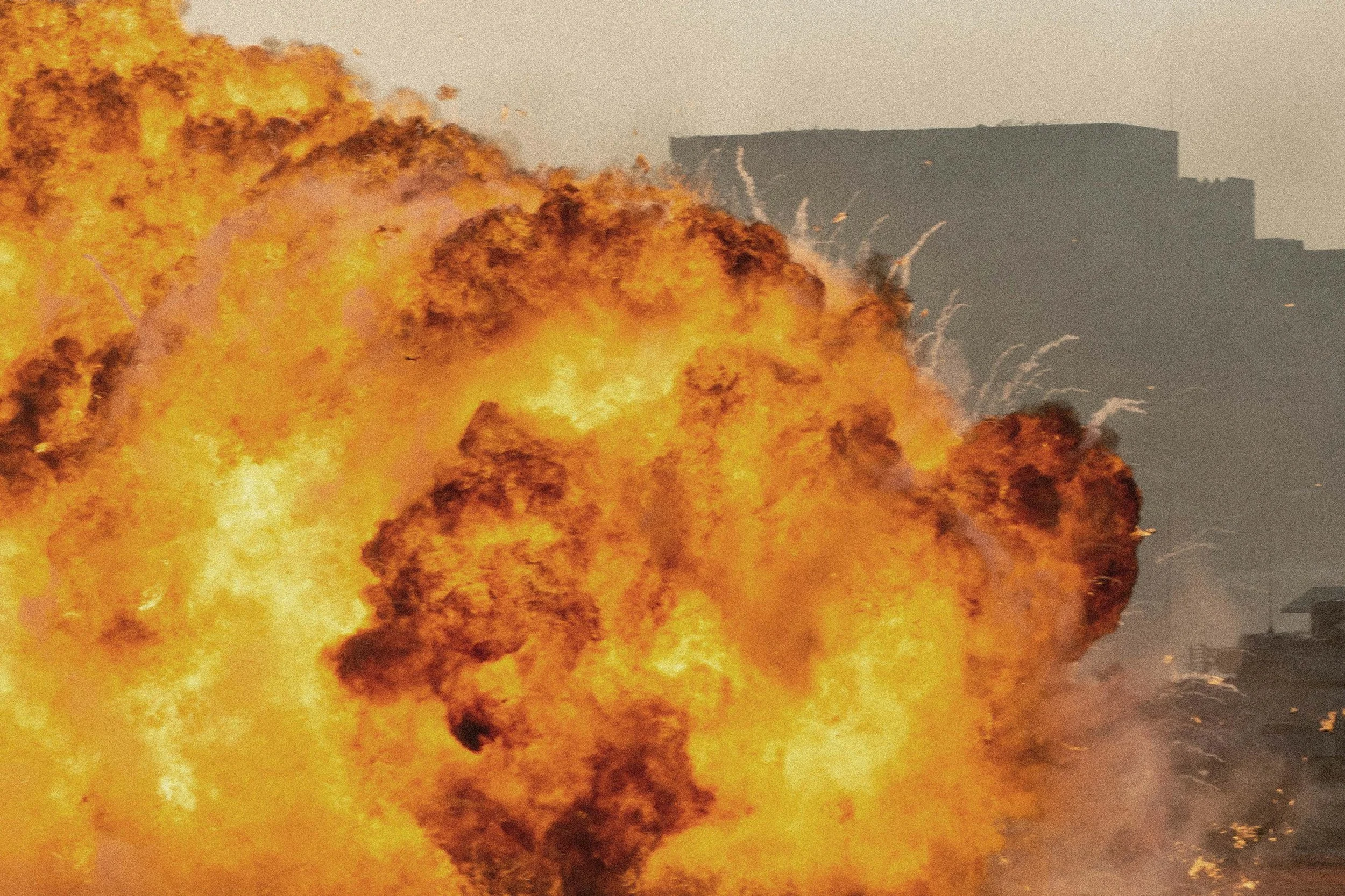 Large explosion with bright orange flames and thick black smoke on an urban street.